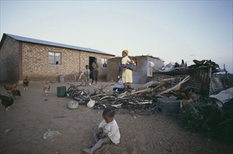 SOUTH AFRICA, Orange Free State, Mother and children outside their home with chickens and cooking