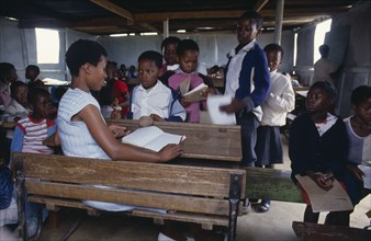 SOUTH AFRICA, Transvaal, Female looking at exercise books of children in school classroom.