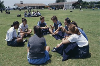 SOUTH AFRICA, Guateng, Johannesburg, Mixed race group of schoolgirls sitting on playing fields