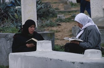 GAZA STRIP, Gaza, Female family members reading the Koran over son’s grave.