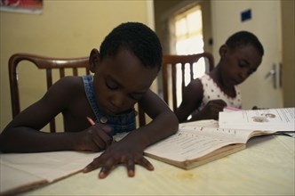 UGANDA, Kampala, Two young children doing homework.