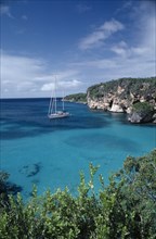 ANGUILLA, Landscape, A yacht sailing on turquoise sea near vegetation covered cliffs