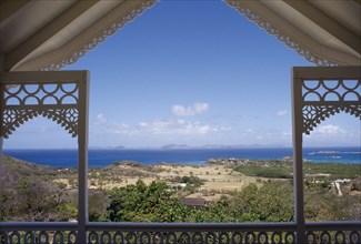 GRENADINES, Mustique, View from a carved Villa balcony over land and trees towards the coastline