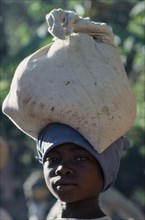 HAITI, People, Children, Portrait of a young girl carrying a full sack on her head