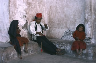 PERU, Puno, Lake Titicaca, Taquile man spinning wool with his two children sitting either side of