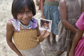 COLOMBIA, Amazonas, Santa Isabel, Macuna Indian girl holding a polaroid photograph of herself.