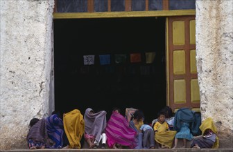 MEXICO, Chiapas, Children sitting in doorway of building wrapped in colourful blankets as