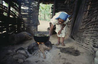 DOMINICAN REPUBLIC, Montesita, Woman cooking over open fire.