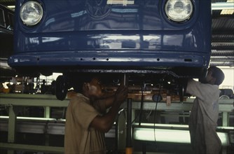 NIGERIA, Lagos, Men working on underside of car on Volkswagen car assembly line.