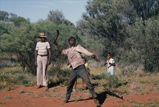 AUSTRALIA, Northern Territory, Alice Springs, Aborigine man throwing a Boomerang with a man and