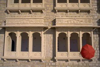INDIA, Rajasthan, Jaisalmer, Hotel Himmatgarth Palace exterior with detail of windows and a red