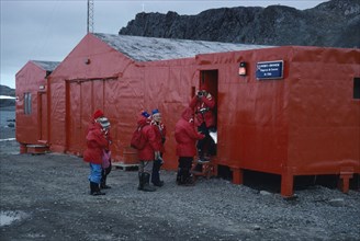 ANTARCTICA, King George Island, Teniente Marsh Station. Tourists wearing red jackets outside Post