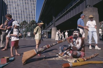 AUSTRALIA, New South Wales, Sydney, Circular Quay. Aboriginal Digeridoo player busking with people