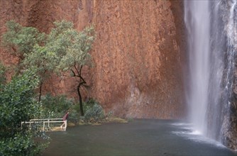 AUSTRALIA, Northern, Uluru, Ayers Rock. Maggie Springs. A woman viewing the cascading waterfall