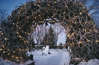 USA, Wyoming, Jackson Town Square. View through Elk Horn Archway decorated with lights towards snow