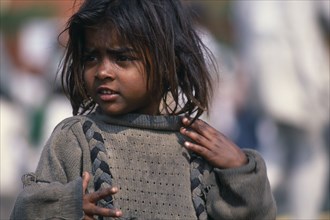 INDIA, Delhi, "Portrait of young street girl wearing dirty,oversized jumper.  Rtnd 2 VKB 15/5/2009"