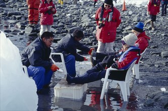 ANTARCTICA, Peninsula Region, Tourists sat on chairs having their boots cleaned before their