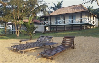 IVORY COAST, San Pédro, Guest chalets at the Hotel Balmer with wooden sun loungers in foreground.