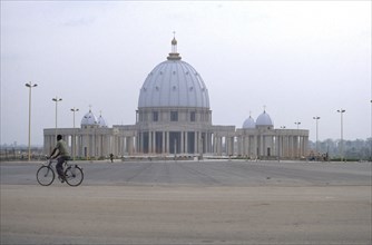 IVORY COAST, Yamoussoukro, Basilique de Notre Dame de la Paix exterior with passing cyclist.