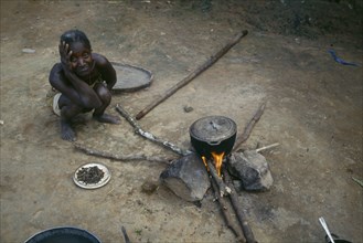 LIBERIA, People, Woman cooking on open fire with cooking pot balanced on stones.