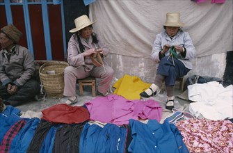 TIBET, Lhasa, Women vendors knitting at clothing stall in street market near the Jokhang Monastery.