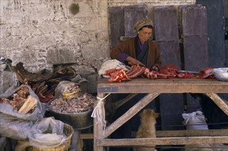 TIBET, Lhasa, Female vendor with yak meat for sale in Jokhang market.