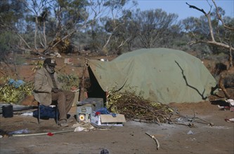 AUSTRALIA, Southern , Oak Valley, Aboriginal man sat on a chair next to a green tent in an