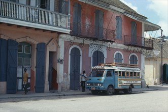 HAITI, Cap Haitien, Street scene with typical colonial style architecture and bus.