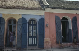 HAITI, Cap Haitien, Street scene with typical colonial style architecture and young woman standing