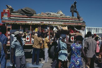 HAITI, Transport, Brightly painted and crowded taptap bus with waiting crowds and food sellers.