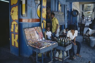 HAITI, Port au Prince, Children and young men outside shop of sweets and drinks vendor with blue