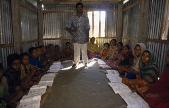 BANGLADESH, Char Kukri Mukri, Teacher and pupils in village school.  Students sit on earth floor of