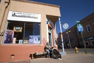 USA, New Mexico, Santa Fe, Native American man feeding his dog outside Father Sky Mother Earth