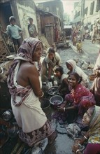 INDIA, West Bengal, Calcutta, Women and children washing at standpipe in street in city slum area.