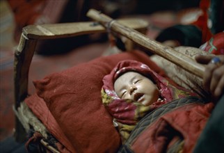 AFGHANISTAN, Children, Kirghiz baby asleep in cot.