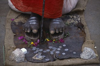 INDIA, Karnataka, Mysore, Cropped shot of sadu standing on nail shoes with coins given by