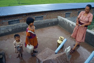 NEPAL, Kathmandu, Woman drawing water from pump on roof of building.