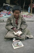 TIBET, Begging, Young boy chanting holy scripts for money.