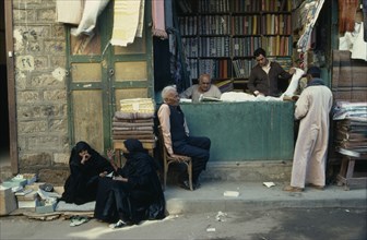 EGYPT, Market, "Market scene.  Vendors, customer and women in conversation outside pavement stall