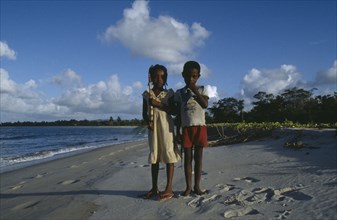 MADAGASCAR, Mananara, Two children standing on shoreline of sandy beach.