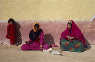EGYPT, Western Desert, Bedouin, "Women and child in colourful dress spinning wool, sitting against