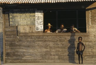 MADAGASCAR, Fort Dauphin, Child standing outside local cinema ticket office with three girls at
