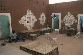 MAURITANIA, Oualata, "Man preparing food in courtyard of buildings with traditional bas-relief