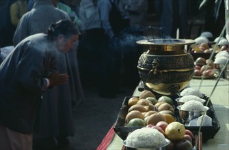 SOUTH KOREA, Religion, Buddhism, Woman praying at an open air altar. Insense burning in a gold urn