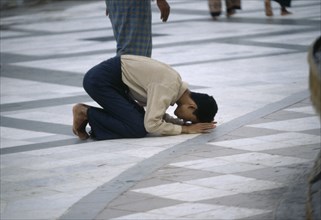 MYANMAR, Yangon, Man praying on floor at Shwedagon Pagoda