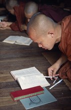 MYANMAR, Insein, Monk at wooden desk with books in Ywama Monastry