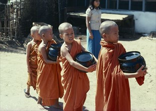 MYANMAR, Rangoon, Novice monks carrying Alms bowls