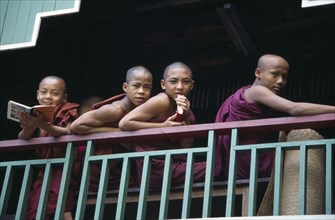 MYANMAR, Insein, Monks leaning on balcony at Ywama Monastry