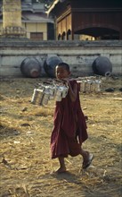MYANMAR, Religion, Buddhism, Young Monk carrying Tiffin Boxes over his shoulder