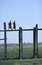 MYANMAR,  Mandalay, Monks walking aross the wooden Amarapura Bridge over the flood plain